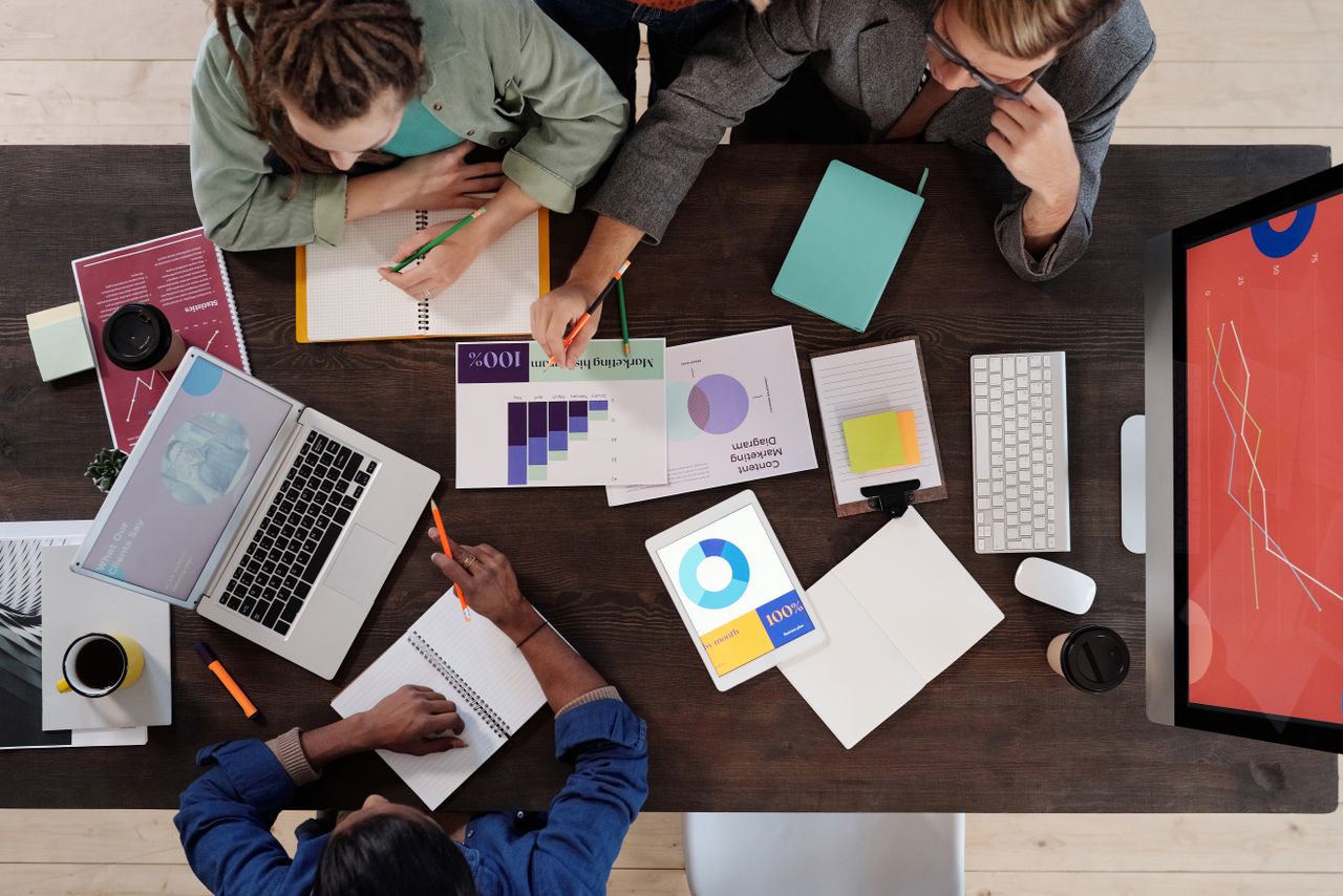 Vue plongeante d’une équipe diversifiée collaborant sur un projet dans un environnement de bureau moderne.